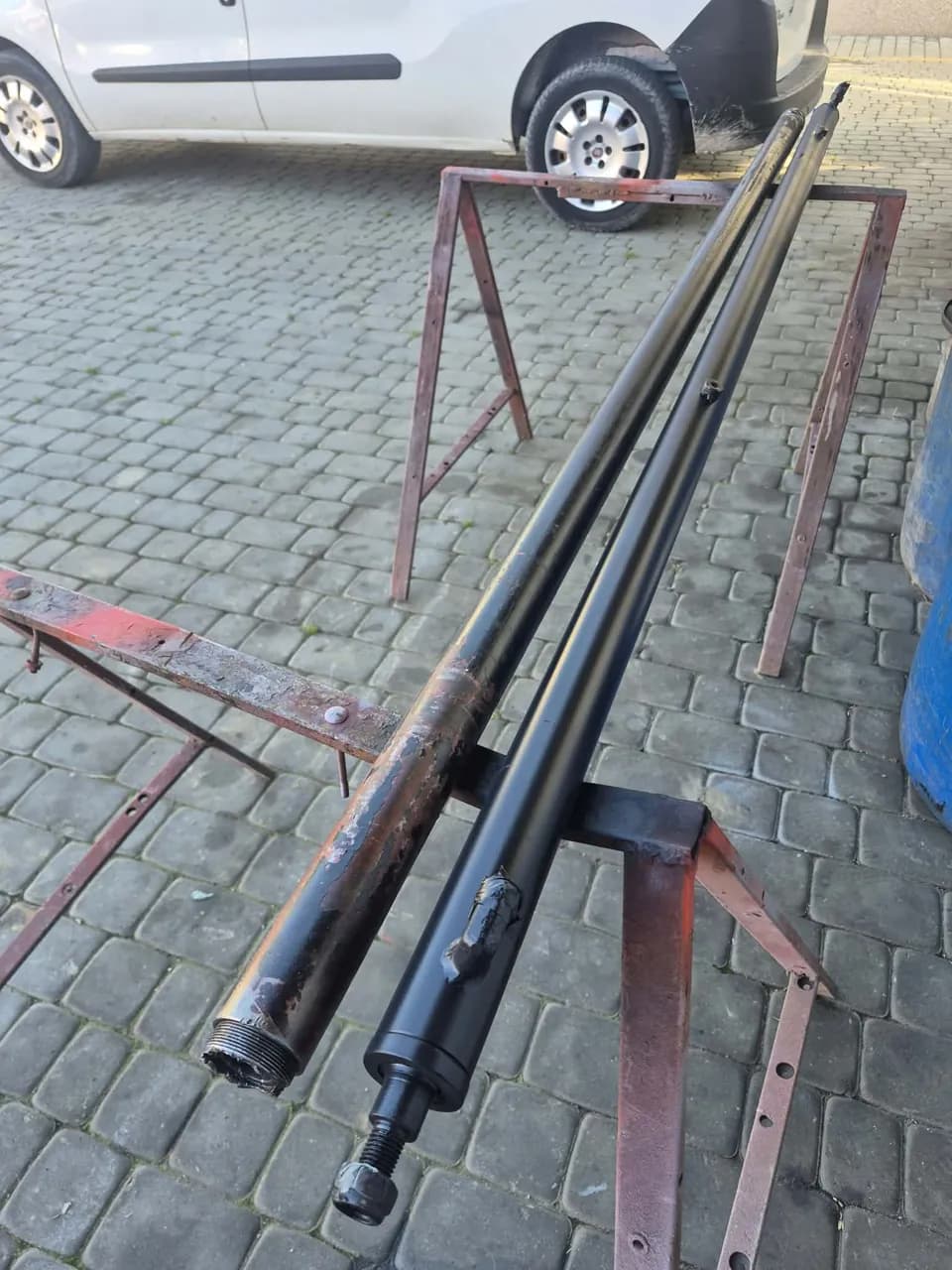 Dwa długie siłowniki hydrauliczne na stalowych kozłach