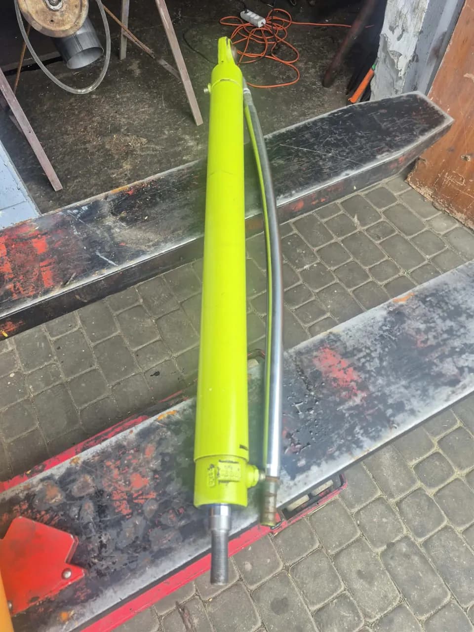 Limonkowy siłownik hydrauliczny z przewodem na widłach wózka paletowego