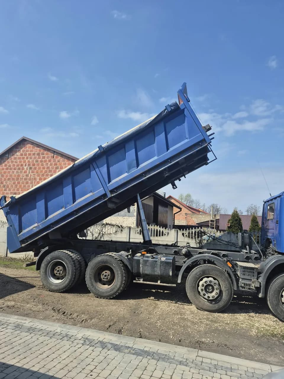 Samochód ciężarowy wywrotka z podniesioną niebieską skrzynią ładunkową