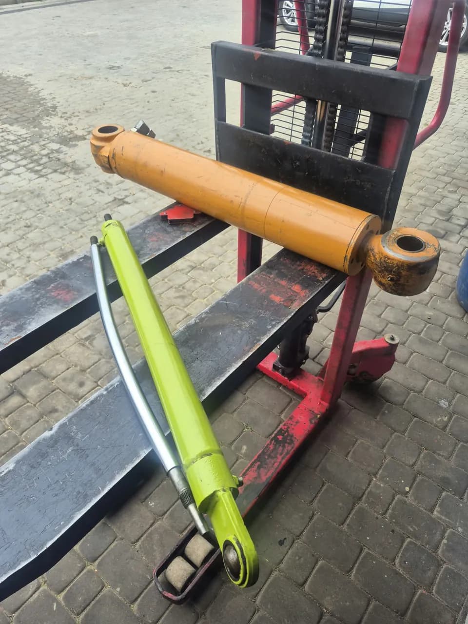 Żółty i limonkowy siłownik hydrauliczny na widłach wózka paletowego